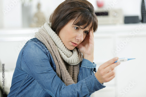 Photography a worried woman holding a thermometer