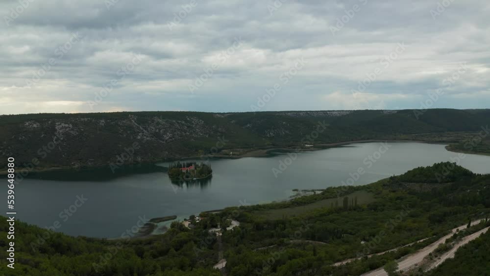 Visovac Island is a beautiful natural wonder in Croatia, known for its stunning landscapes and lush vegetation. This aerial footage shows off the island's dramatic landscapes at dawn, from its towerin Visovac Island is a beautiful natural wonder in Croatia, known for its stunning landscapes and lush vegetation. This aerial footage shows off the island's dramatic landscapes at dawn, from its towerin