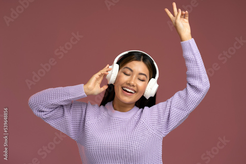 Valokuva Crazy asian woman in headphones singing rejoicing and showing peace gesture