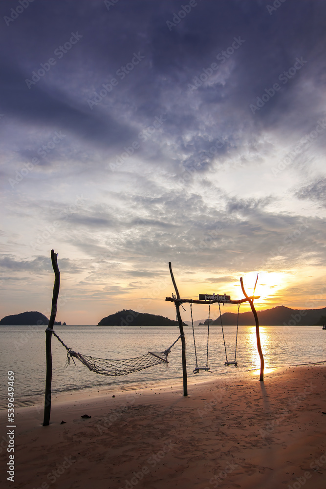 Sunset sea beach travel island with rope hammock and wood swing landmark and twilight cloud sky background landscape in Koh Mak Thailand Sunset sea beach travel island with rope hammock and wood swing landmark and twilight cloud sky background landscape in Koh Mak Thailand