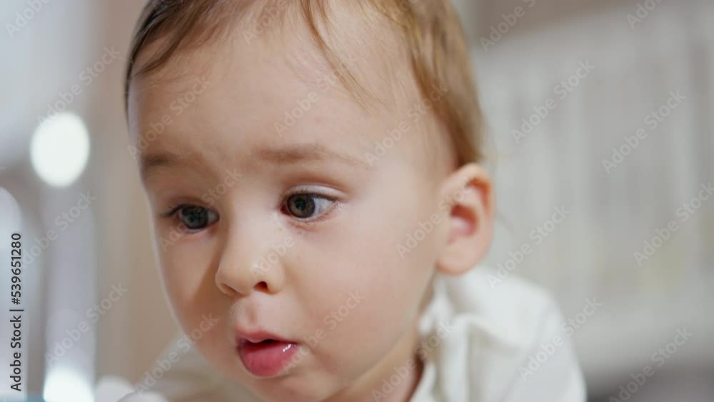 Adorable Caucasian child looking down interested in something. Portrait of a little baby boy busy with a toy. Close up. Blurred backdrop. Adorable Caucasian child looking down interested in something. Portrait of a little baby boy busy with a toy. Close up. Blurred backdrop.