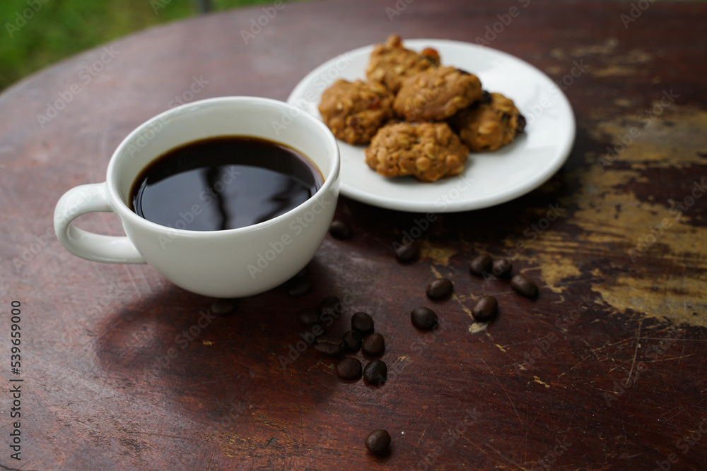 Black coffee cup with cookies on wooden floor, black coffee in the morning to drink with cookies.