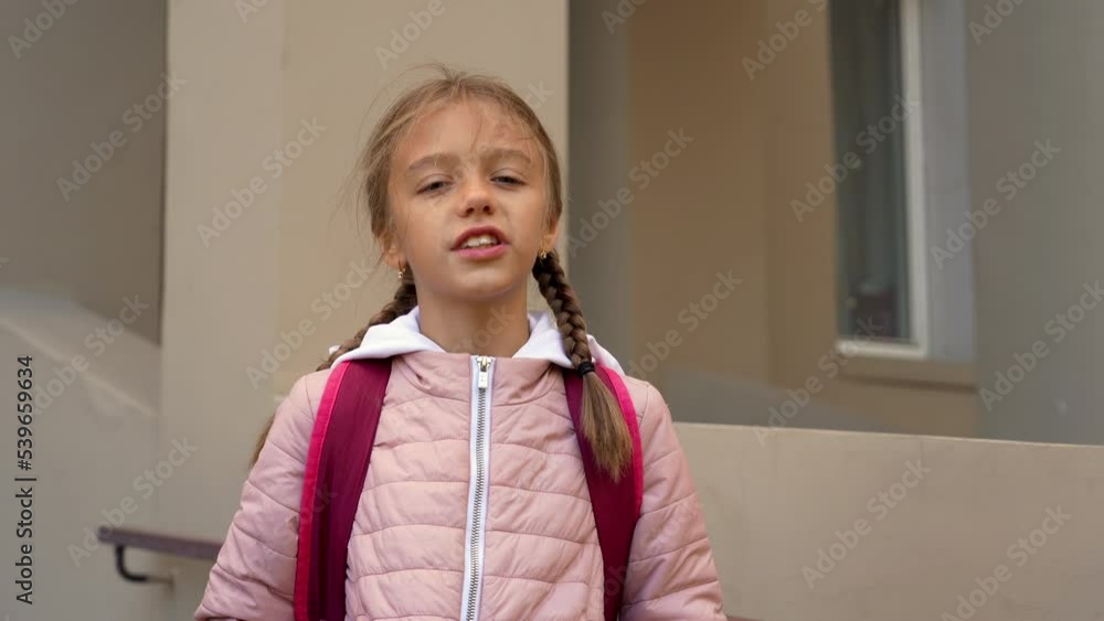 School-age girl looking at camera and speaking, talking, reading text of poems, standing on porch at home School-age girl looking at camera and speaking, talking, reading text of poems, standing on porch at home