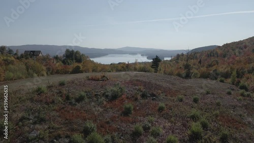 Aerial footage of the foliage surrounding Newfound Lake under a clear blue sky photo