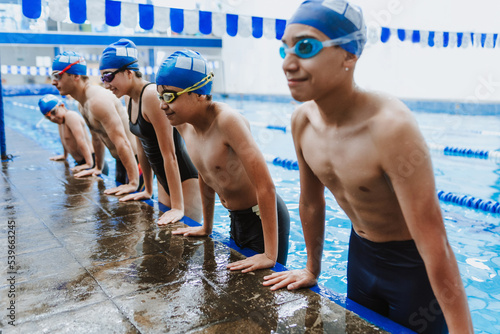 latin young man swimmer athlete wearing cap and goggles in a swimming training holding On Starting Block In the Pool in Mexico Latin America	