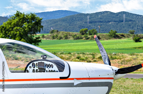 Single engine ultralight airplane waiting to take off at the airfield with blue sky and field background