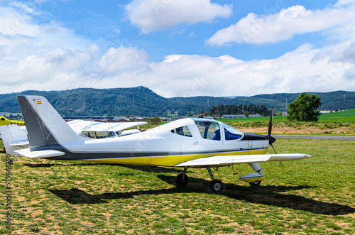 Single engine ultralight airplane waiting to take off at the airfield with blue sky and field background