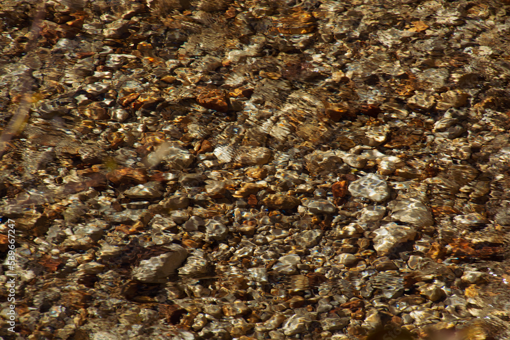 blurred water surface of a clear creek with beatuiful golden colored stones blurred water surface of a clear creek with beatuiful golden colored stones