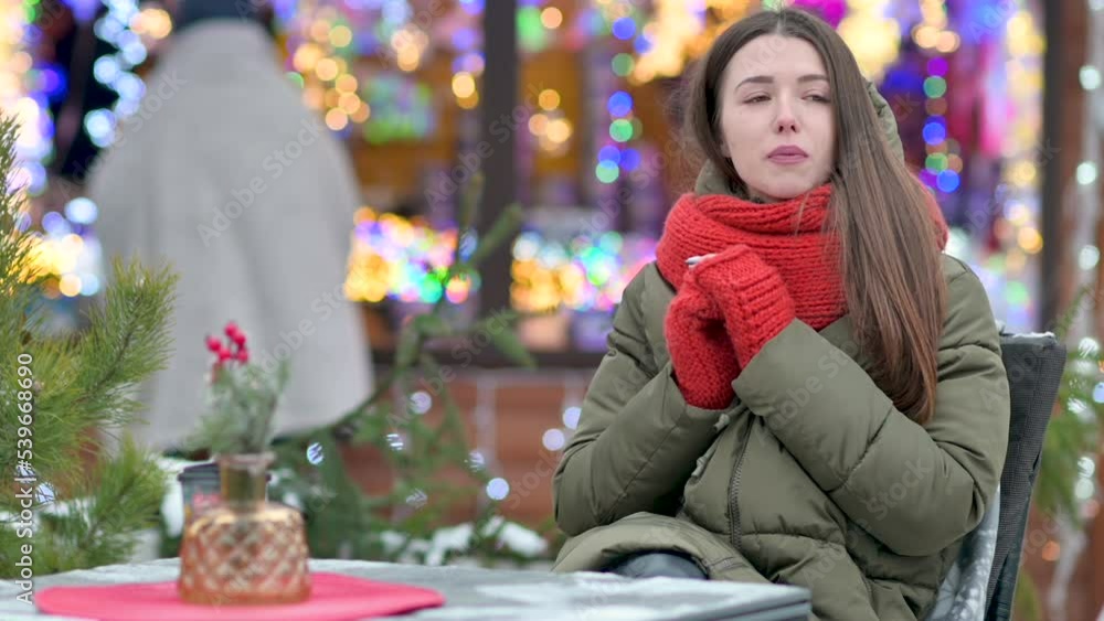 Portrait of a young happy girl warms her frozen hands against the background of bright festive lights. holiday season. merry christmas Portrait of a young happy girl warms her frozen hands against the background of bright festive lights. holiday season. merry christmas