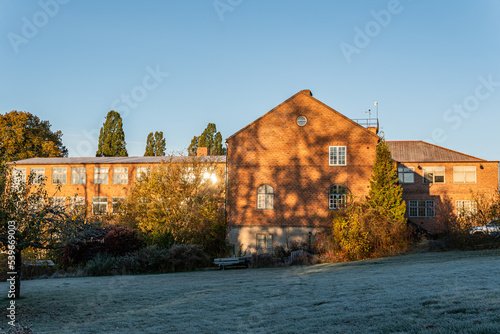 Sweden, Knislinge – October 30, 2022: Warm sunlight on ancient building from bricks. Morning frost on grass in autumn.  photo