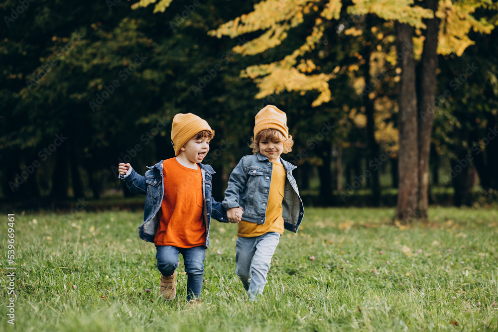 Two boys brothers running in an autumn park Two boys brothers running in an autumn park