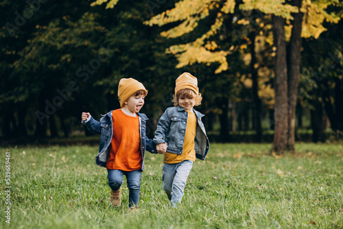 Two boys brothers running in an autumn park