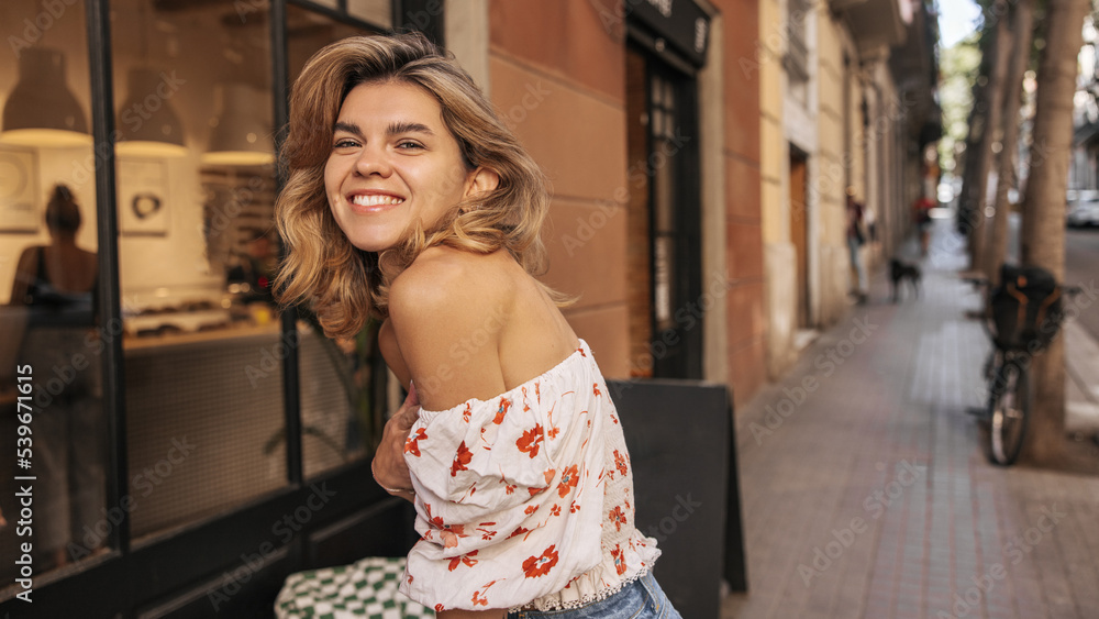 Happy young caucasian lady smiling broadly looking at camera relaxing outdoors in summer. Blonde girl with wavy hair wears white blouse. People freedom and joy concept Happy young caucasian lady smiling broadly looking at camera relaxing outdoors in summer. Blonde girl with wavy hair wears white blouse. People freedom and joy concept