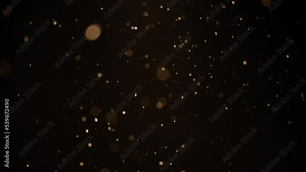 Gold colored dust bokeh particles floating in the air. Slow motion. Gold colored dust bokeh particles floating in the air. Slow motion.