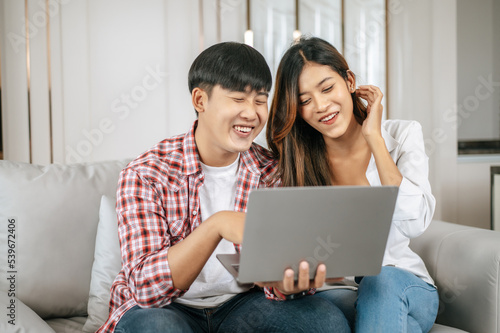 Attractive Young couple use laptop computer working with happiness