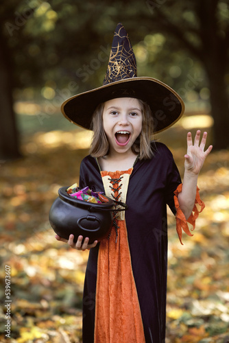 Vertical image of girl in witch outfit and standing in the woods