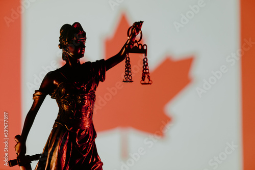 Lady Justice and Canada flag in the background. Law and court concept