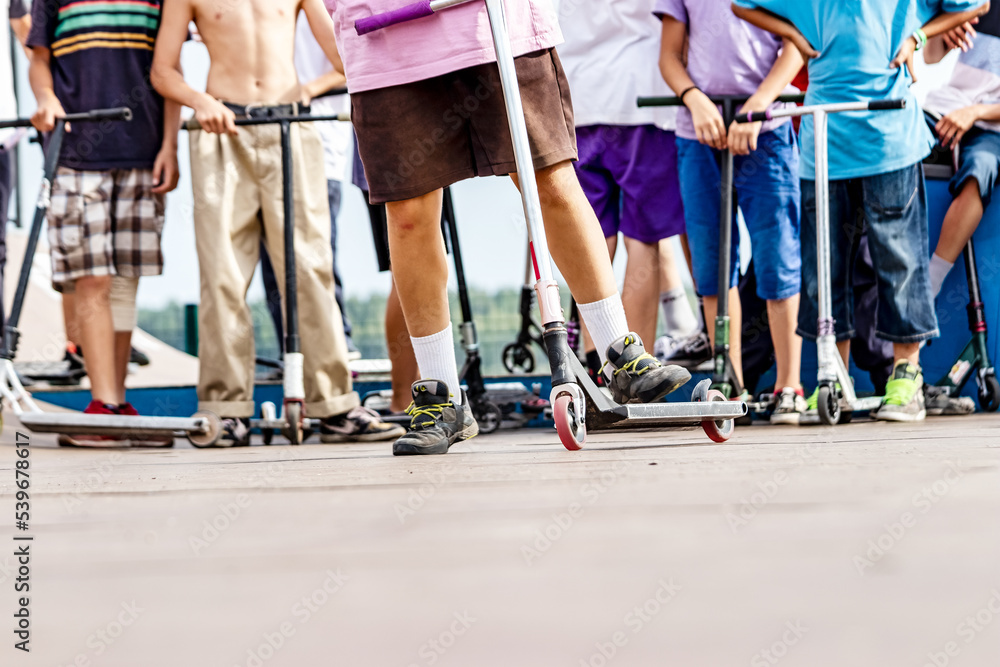 Obraz premium Boys with scooters and skate park. Extreme jumping on a scooter. The concept of a healthy lifestyle and sports leisure.