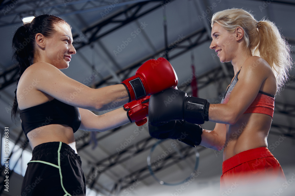 Sportive young women wearing sports uniform and boxing gloves workout at sports gym. Sport, workout, strength and active lifestyle