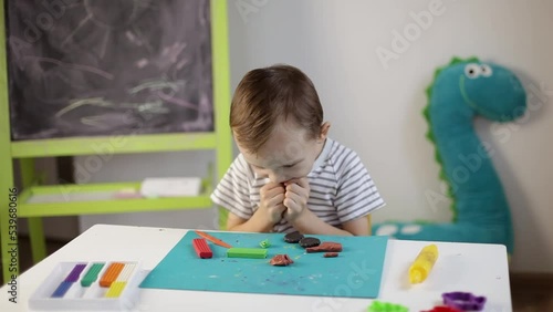 a little boy sculpts from plasticine on the table. Tactile activity, fine motor skills.