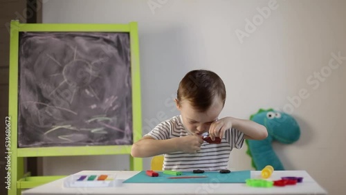 a little boy sculpts from plasticine on the table. Tactile activity, fine motor skills.