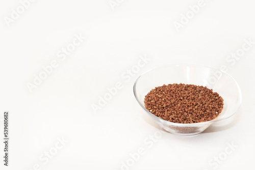 small grains of natural brown buckwheat in a transparent glass plate