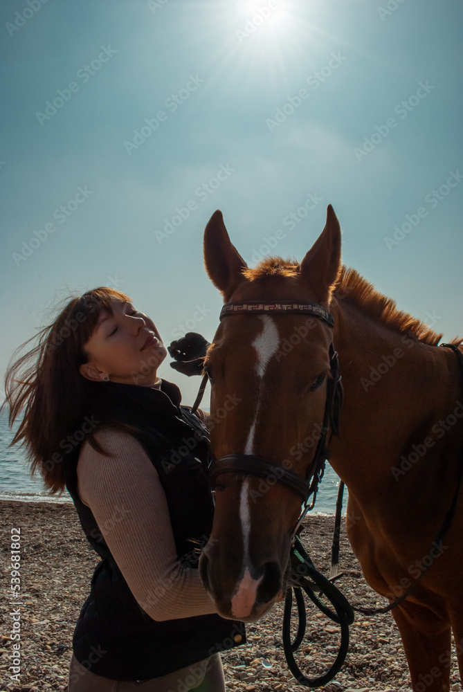 Fototapeta premium Selective focus. Girl and horse. Horse riding by the sea.