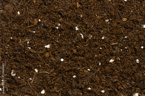 Organic potting compost, background, from above. Soil, growing medium and culture substrate for sowing. Made of moderately decomposed raised bog peat, bark humus, wood fibers, sand and NPK fertilizer.