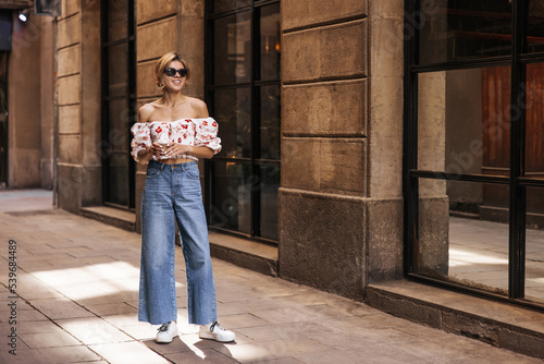 Wallpaper Mural Full length stylish young caucasian girl enjoys outdoor activities. Blonde woman wears sunglasses, blouse and jeans in summer. People emotions, lifestyle and fashion concept Torontodigital.ca