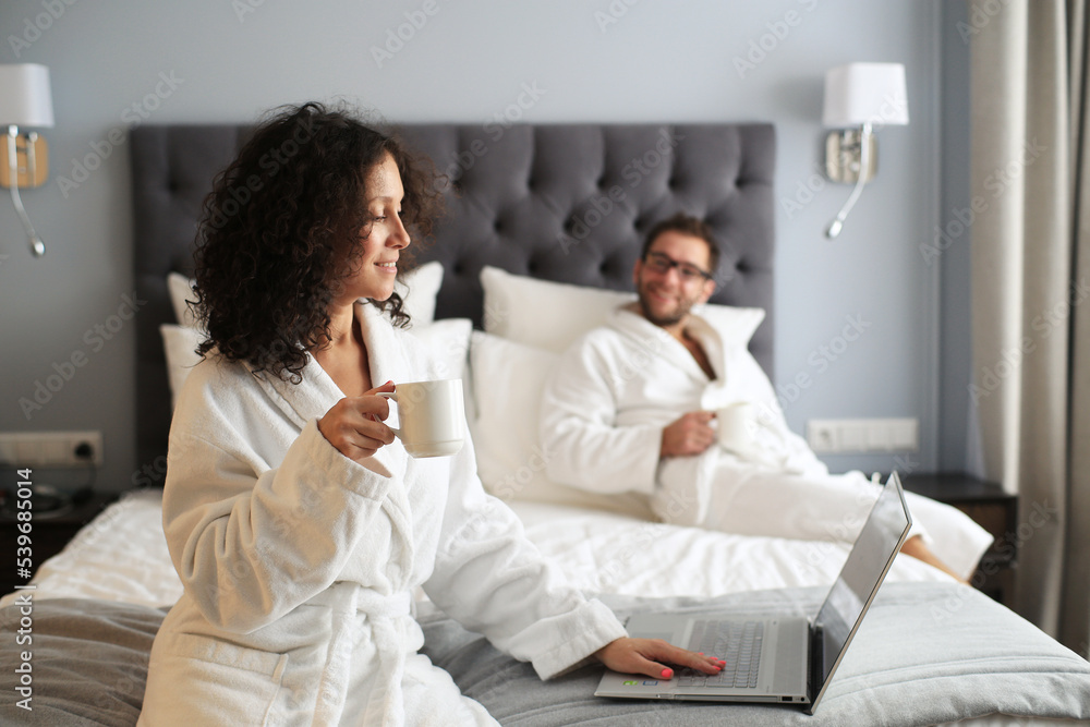 Couple in white bathrobe on a bed in a hotel. Morning in the hotel room. Couple in white bathrobe on a bed in a hotel. Morning in the hotel room.