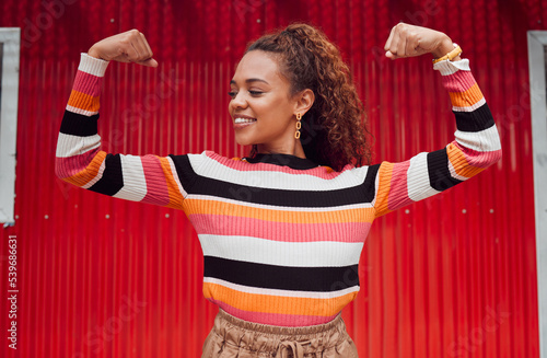 Beauty, fashion and strong with a black woman flexing her muscle or bicep outdoor on a red background. Smile, proud and style with an attractive young female posing for strength or empowerment
