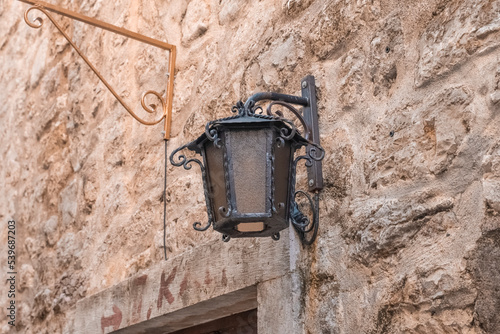 an old street lamp attached to the stone wall of an old building. Old lighting fixtures. An antique lamp
