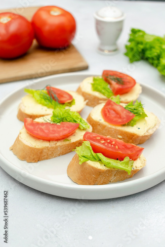 Bruschetta sandwich bread toast with soft white cheese ricotta,fresh tomatoes,basil greenery on a wooden cutting board.Tasty healthy vegetarian food,Italian cuisine appetizer. top view flat lay