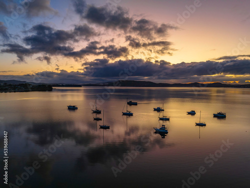 Aerial sunrise waterscape with boats  rain clouds and reflections
