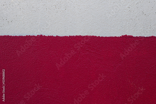 Old rough wall texture painted in two messy horizontal strips of white and red colors. Abstract background with empty space for text © Marta Nogueira