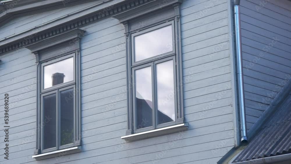 Windows of an old gray painted wooden house on a sunny day, gray painted wood frame, old residential house exterior, downtown Liepaja (Latvia), distant medium shot Windows of an old gray painted wooden house on a sunny day, gray painted wood frame, old residential house exterior, downtown Liepaja (Latvia), distant medium shot