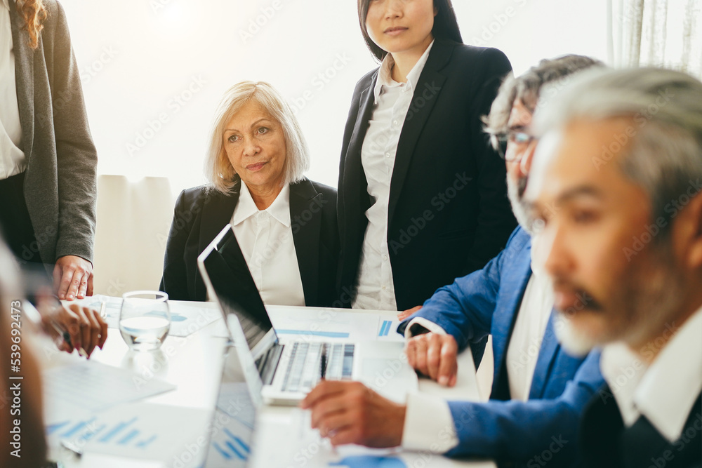 Multiracial business people working inside bank office - Focus on senior woman face Multiracial business people working inside bank office - Focus on senior woman face