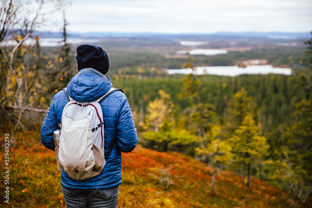 Man traveler in blue jacket with backpack hike in autumn forest in Finland Lapland. Hiking travel and adventure. Man traveler in blue jacket with backpack hike in autumn forest in Finland Lapland. Hiking travel and adventure.