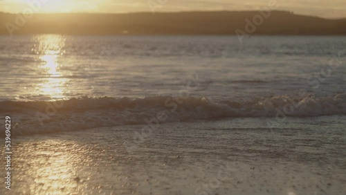 A beautiful golden sunset over the beach waves in Devon, UK photo