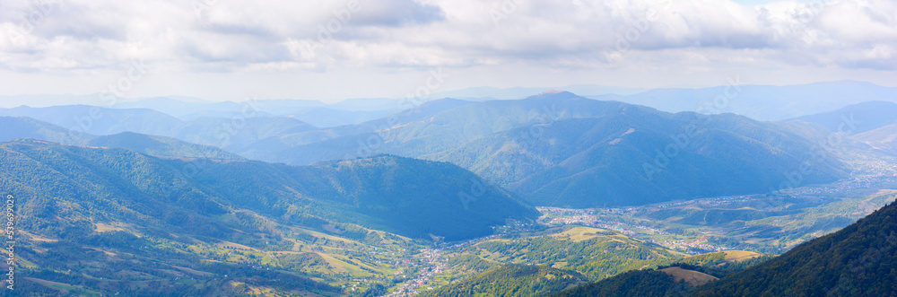 mountainous rural landscape of transcarpathia. kolochava village down in the valley observed from the top of a hill. distant ridge beneath a cloudy sky. nature scenery in morning light