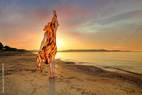 A woman standing on the beach at the sunset