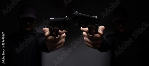 Close up of men hands with aiming gun on a black background.