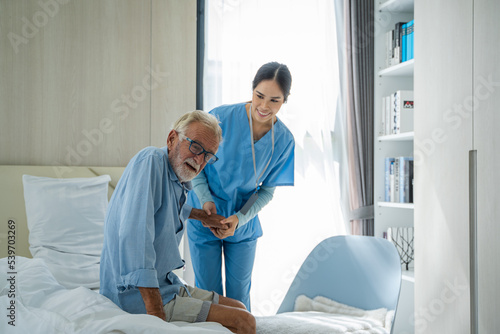Asian women caregiver take care senior disabled man on wheelchair Nurse support disabled senior man patient to walk at nursing home