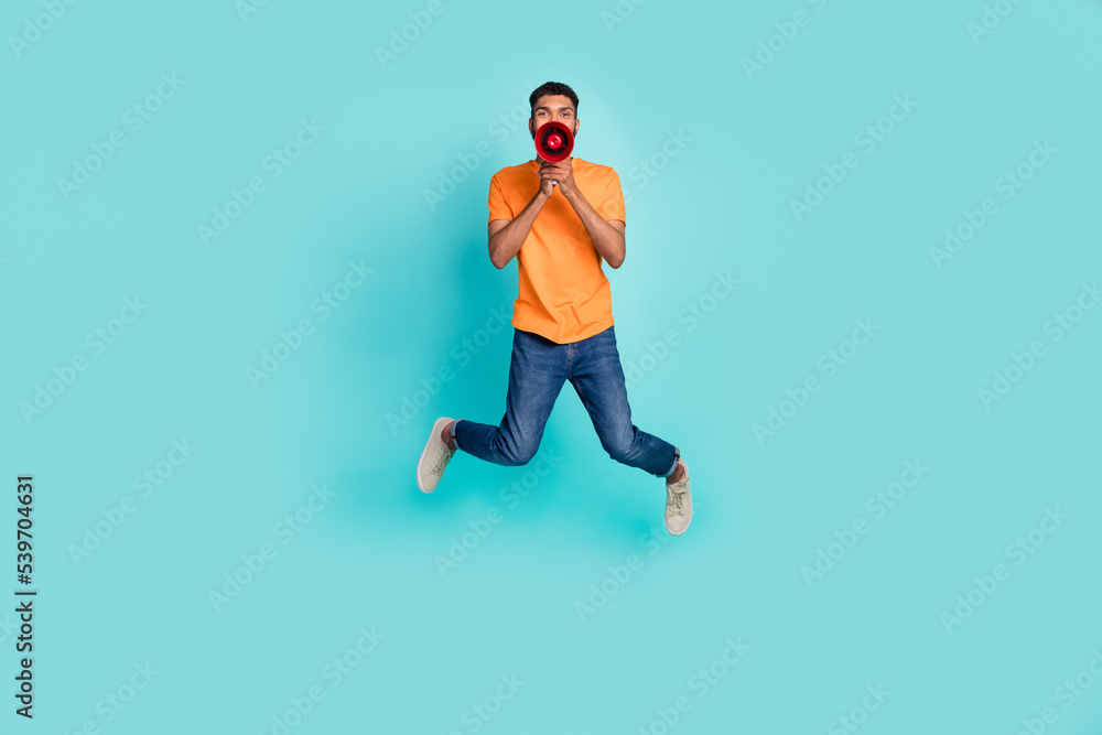 Full body photo of overjoyed person jumping hands hold loudspeaker say isolated on turquoise color background