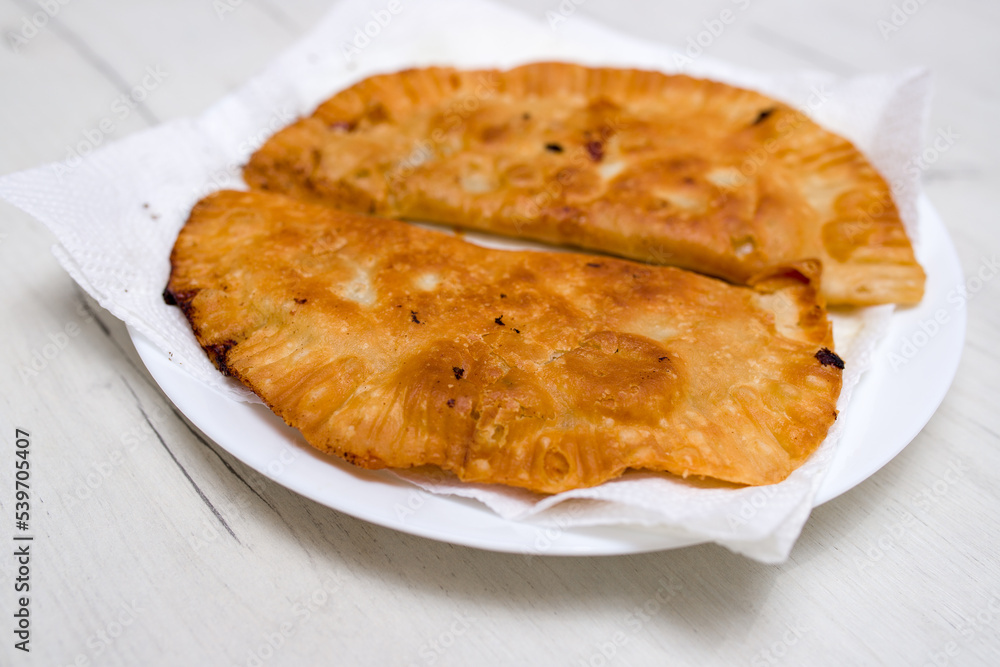 Fried pork and beef patties on a white plate. Delicious crust on pies. Top view. Fried pork and beef patties on a white plate. Delicious crust on pies. Top view.
