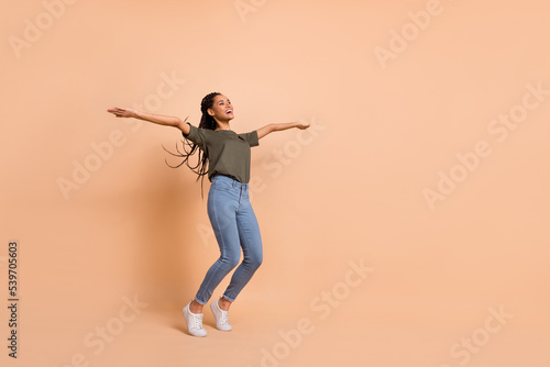 Full body portrait of positive pretty lady raise hands enjoy free time isolated on beige color background