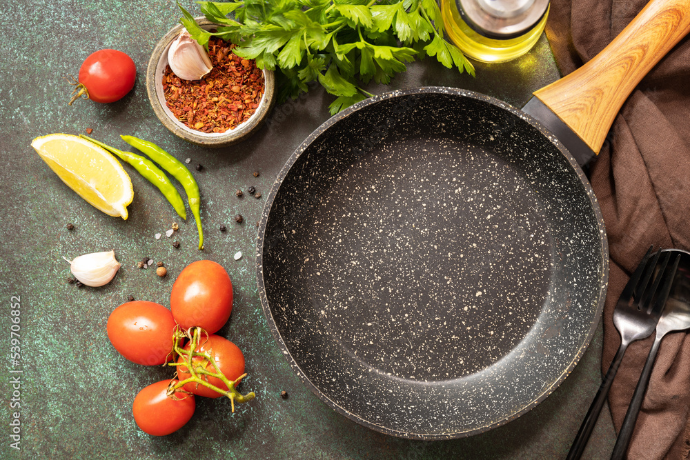 Food cooking background with Frying pan. Empty skillet, vegetables, spices and herbs on dark table background. View from above. Food cooking background with Frying pan. Empty skillet, vegetables, spices and herbs on dark table background. View from above.