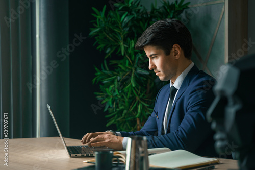 Businessman working with laptop in modern office. General manager,ceo. Young handsome confident man in suit sitting at table. Executive business leader. Entrepreneur career.Accountant bank workplace