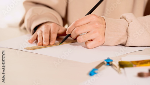 Cropped view of woman drawing with pencil and ruler near compass at home.