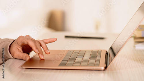 Cropped view of freelancer using laptop touchpad on desk.